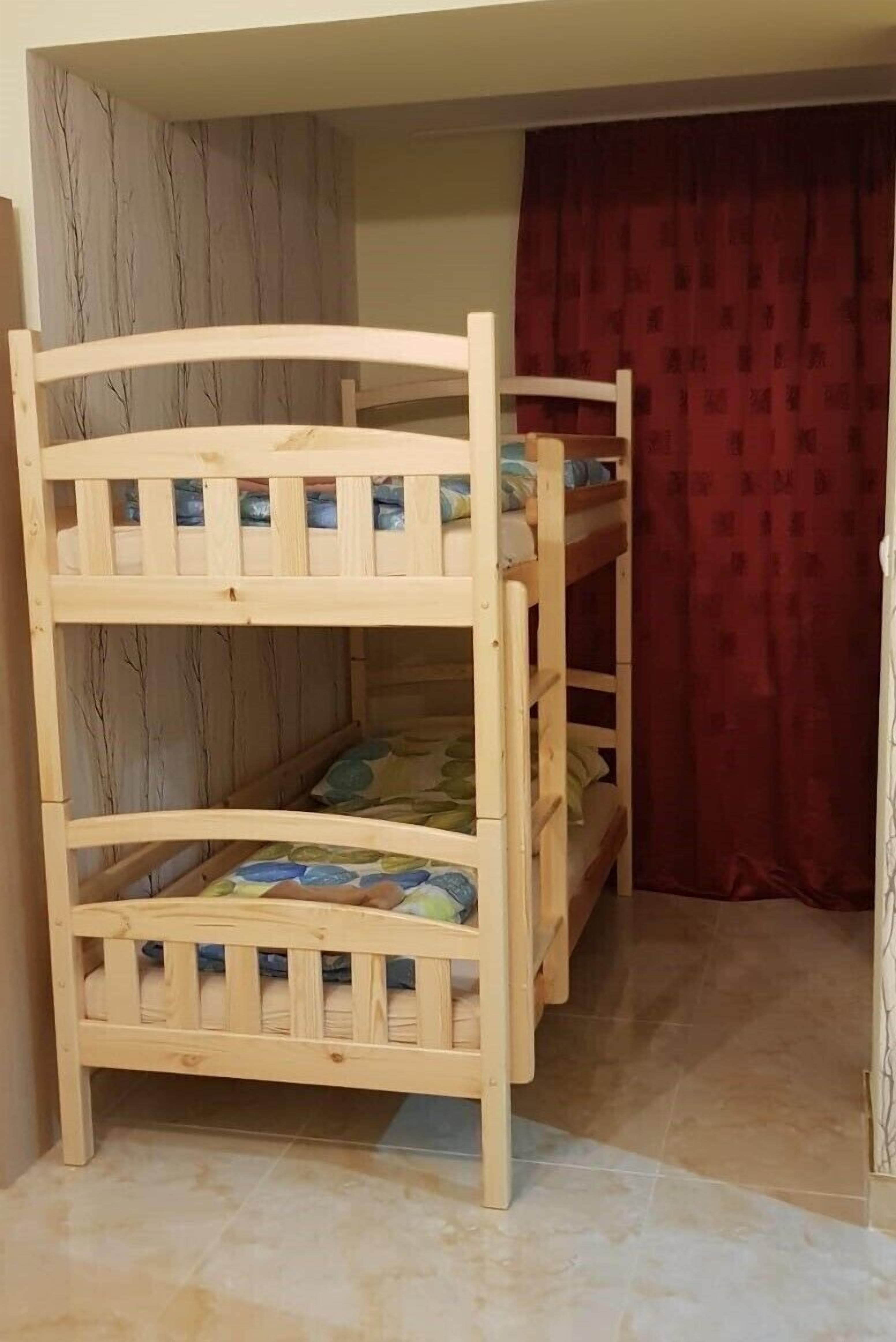 Ein Etagenbett mit zwei Schlafstellen, einem roten Vorhang und einer Wand mit vertikalem Muster.