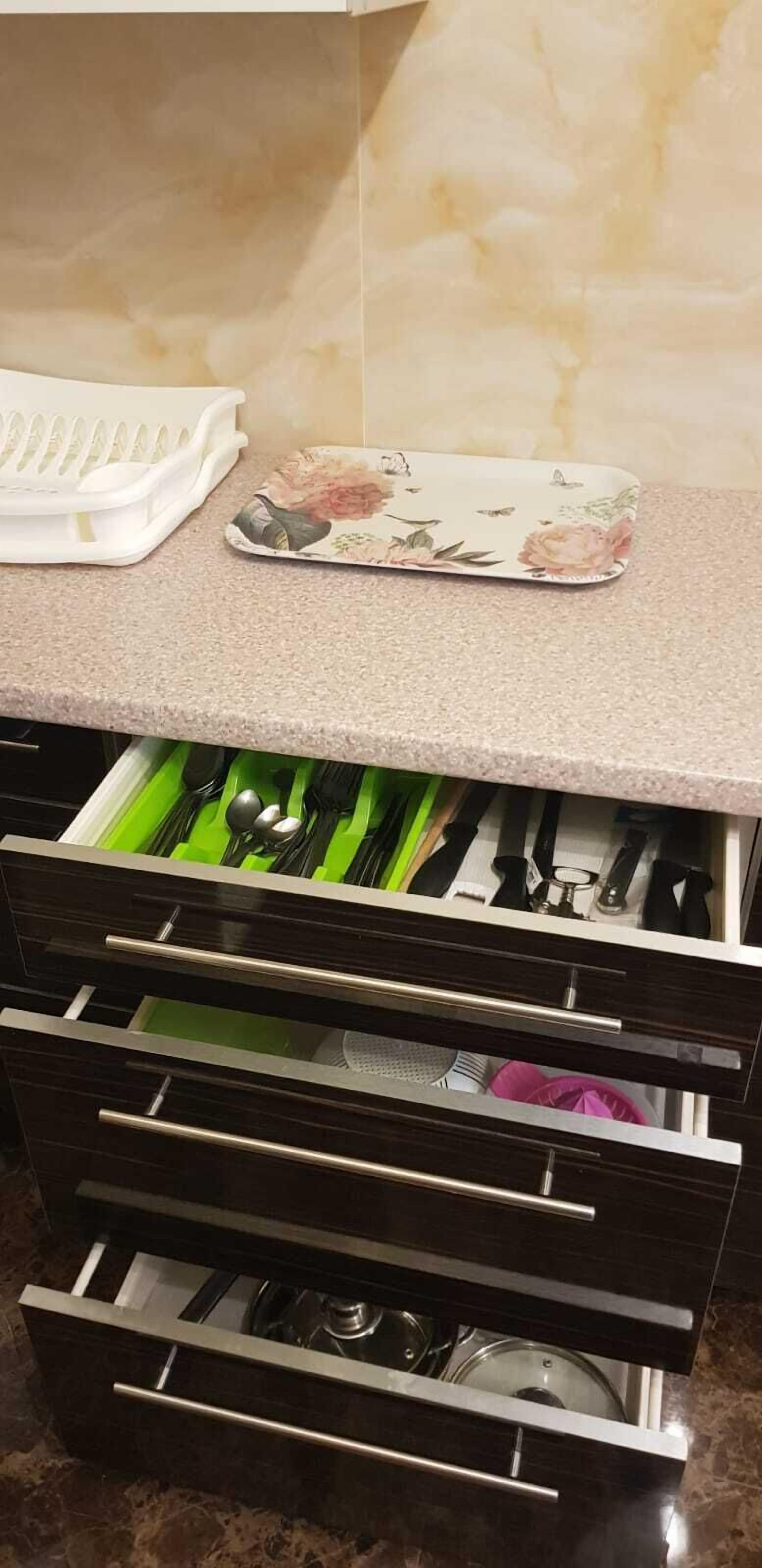 Una cocina con mostrador, una bandeja floral y un cajón con utensilios.