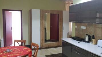A compact kitchen with a dining area, a wardrobe, and a kitchenette.
