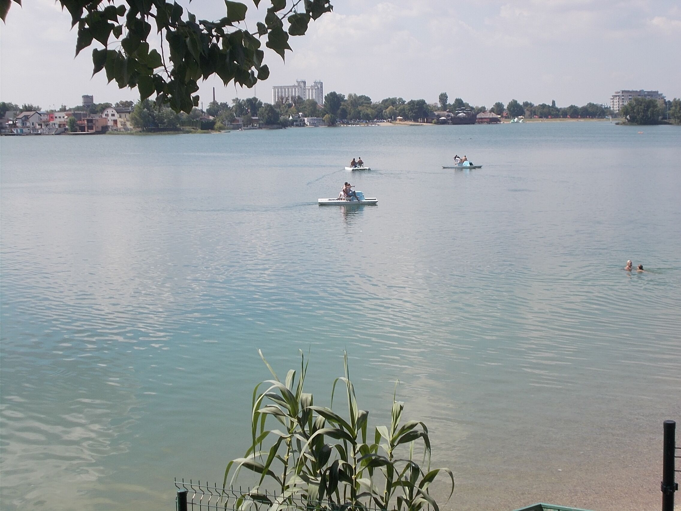 Ein ruhiger See mit Booten und Menschen.