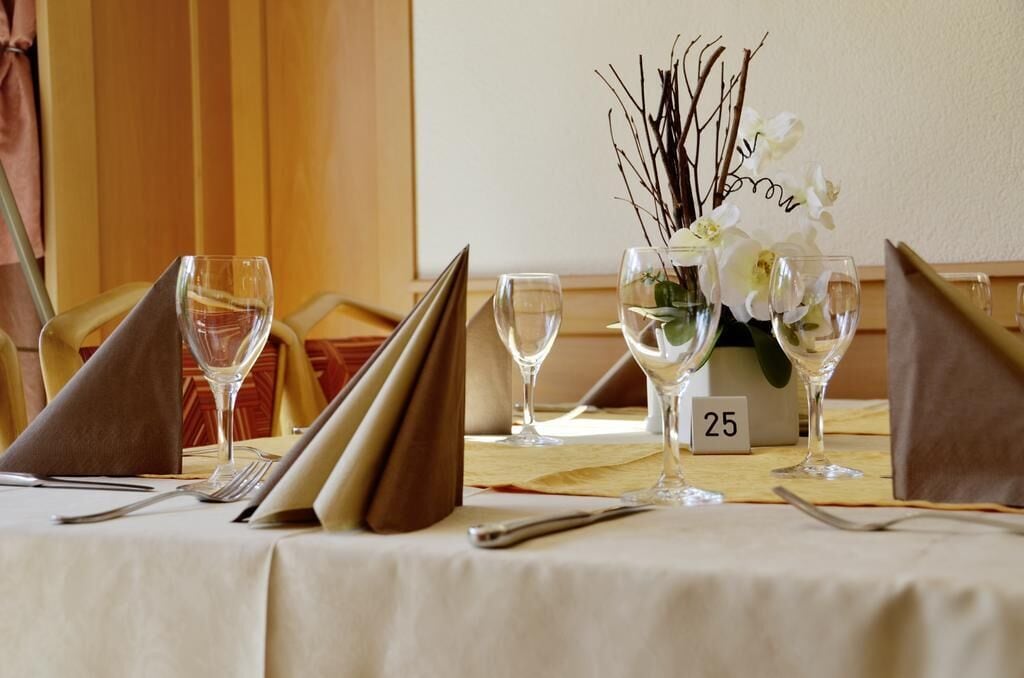 Mesa servida con copas de vino, un florero con flores blancas y un número indicando la mesa 25.