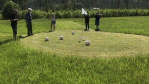 Un campo cubierto de césped con un asta de bandera y varias personas de pie.