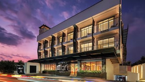 A modern hotel with a prominent entrance, multiple balconies, and a well-lit facade. - Aloft by Marriott Bali Seminyak (Keroboken Kelod)