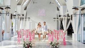 A modern interior with a high ceiling and skylights, featuring a central aisle with pink decorations and floral arrangements. - Aloft by Marriott Bali Seminyak (Keroboken Kelod)