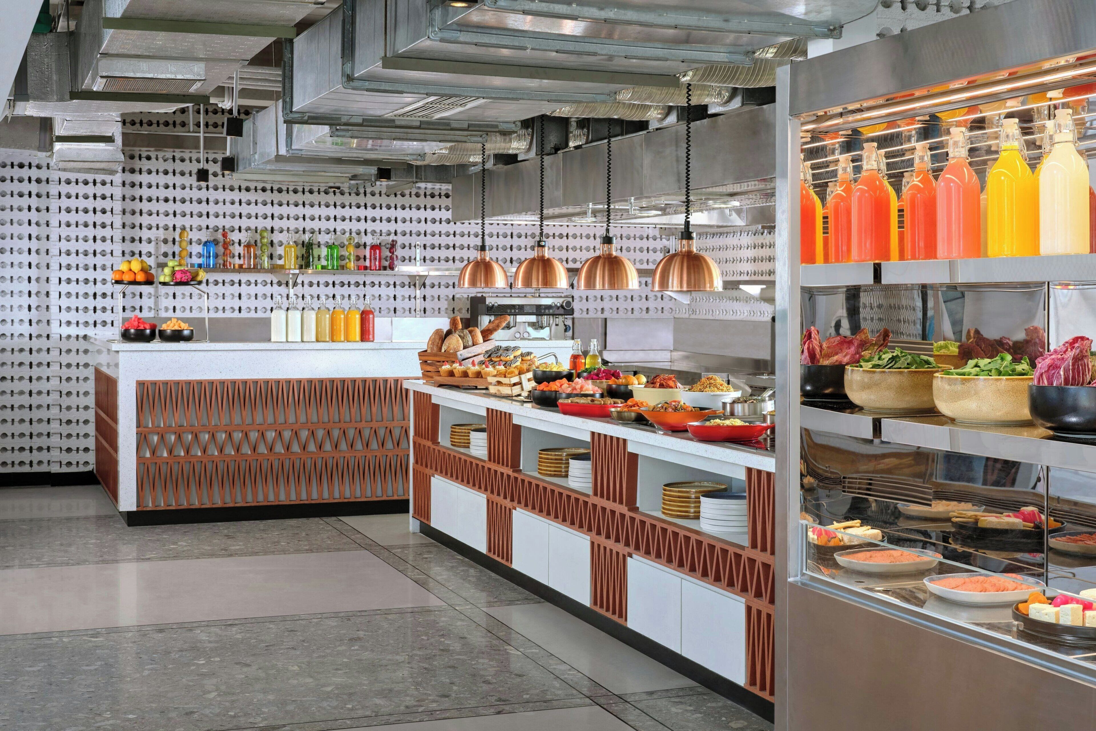 Una cucina moderna con isola centrale, elettrodomestici in acciaio inossidabile e diverse provviste esposte sugli scaffali.