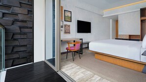 Quarto de hotel moderno com uma cama, uma escrivaninha e uma cadeira.
