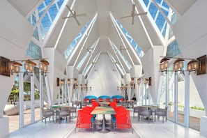 Un vaste espace dédié à la salle à manger, doté de hauts plafonds, de grandes fenêtres et de mobilier moderne.