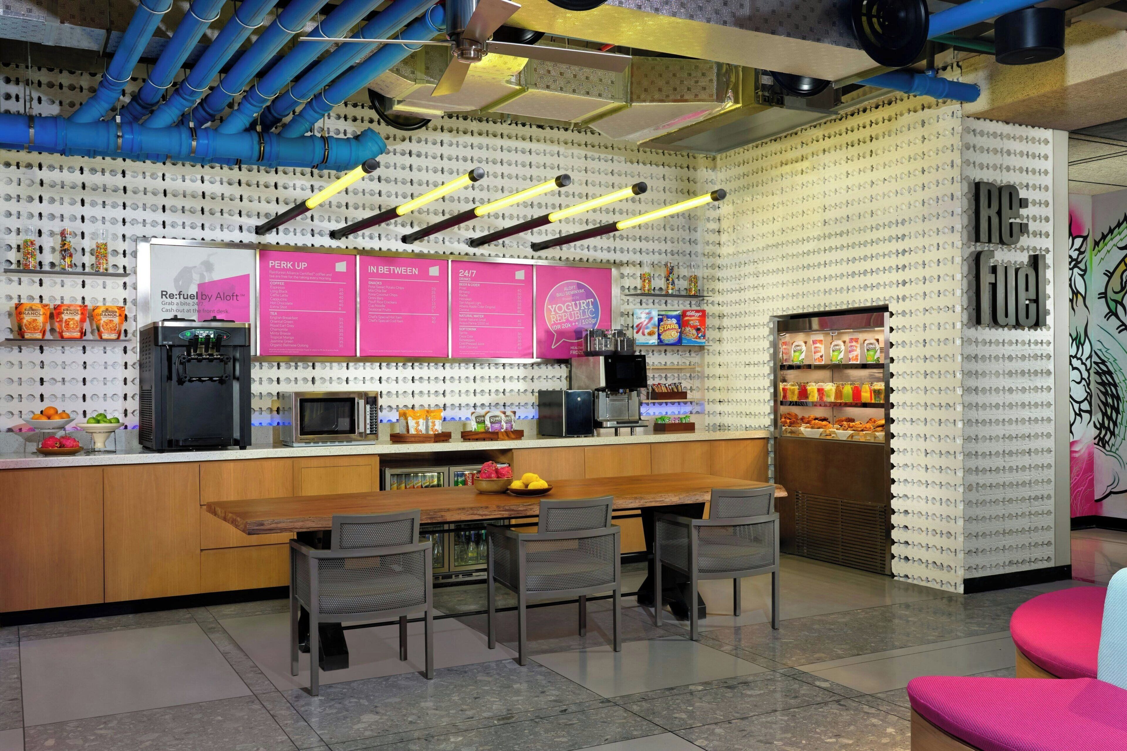 Een modern café met een centraal bedieningspunt, een zithoek en een menubord.