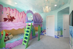 A child's bedroom with a bed, a ladder, and a mural of a sea scene.