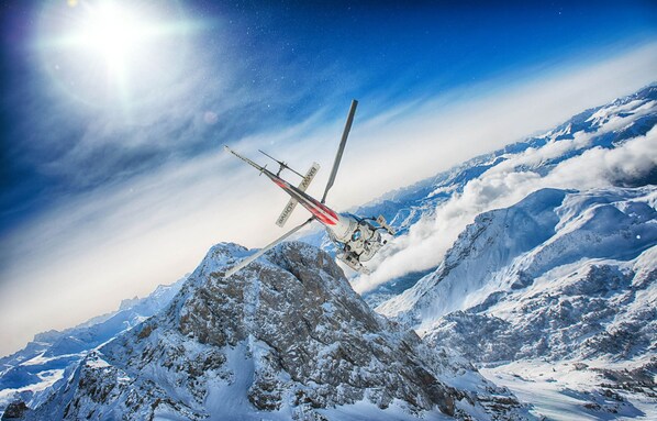 Un helicóptero sobrevolando una cordillera nevada.