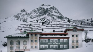Un hotel llamado HOTEL EDELWEISS con un estilo arquitectónico tradicional, situado en una zona montañosa nevada.