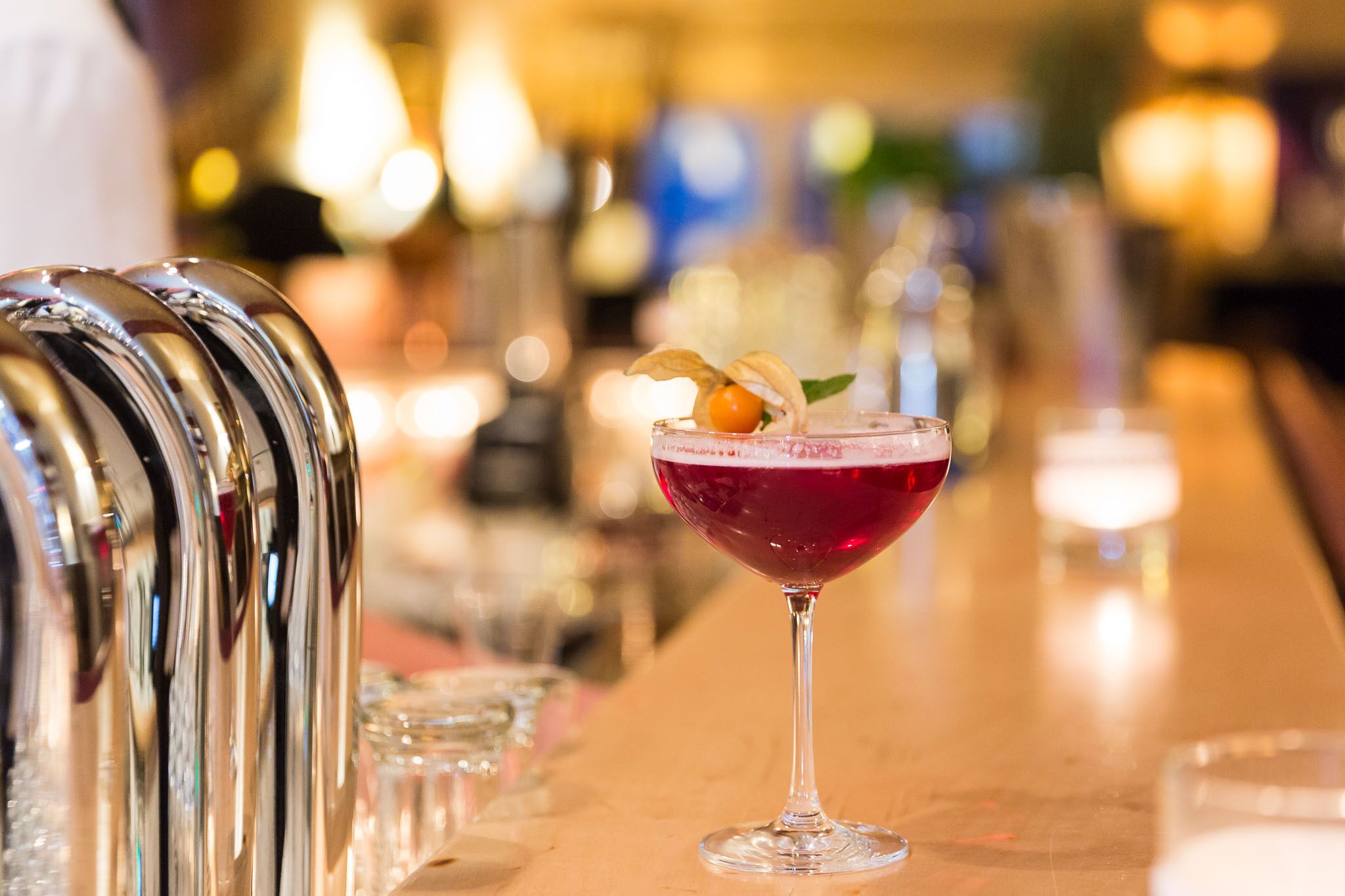 Eine Bar mit Cocktailglas, Barutensilien und unscharfem Hintergrundbereich.