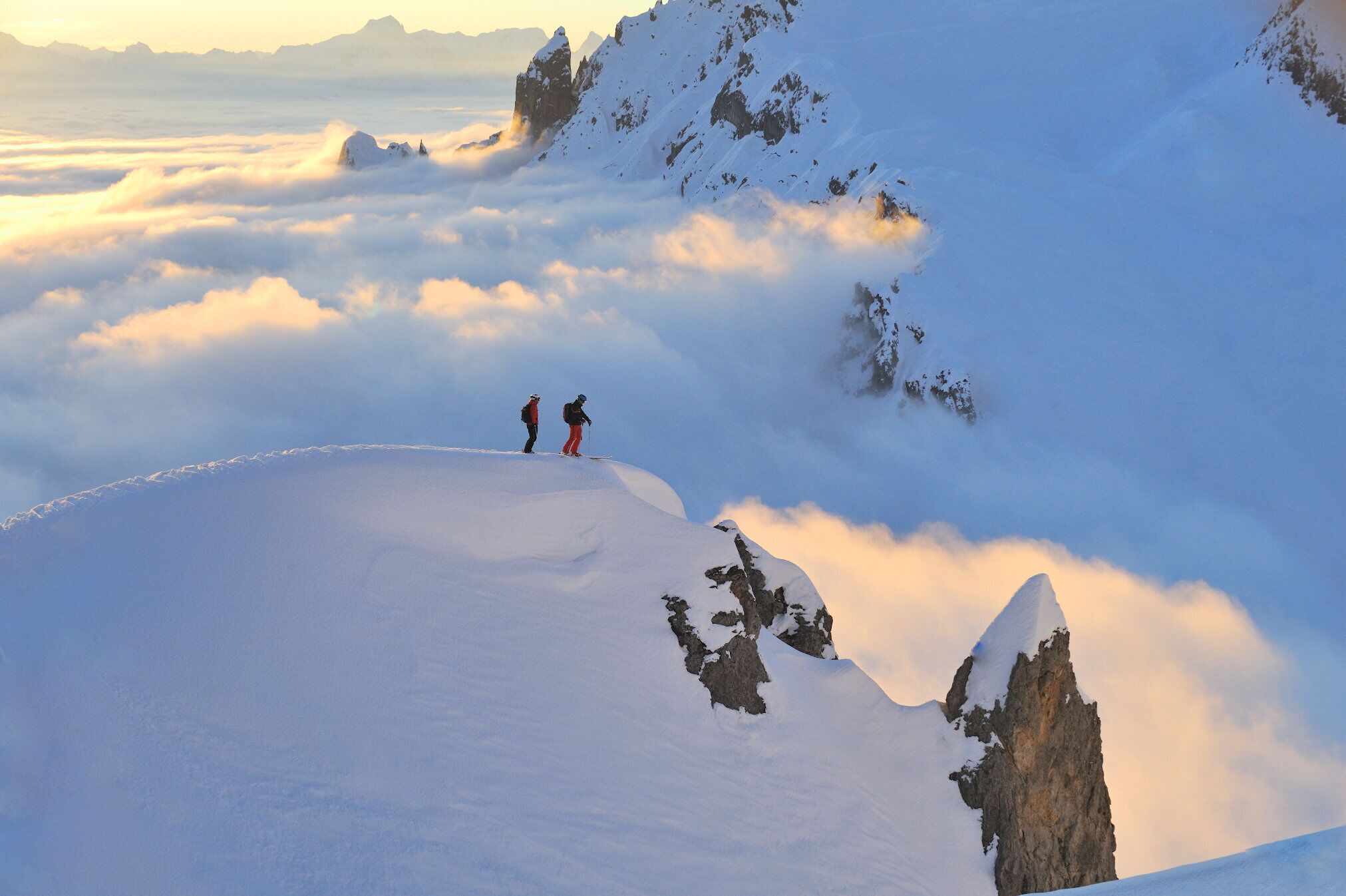 A snowy mountain landscape with two hikers on a ridge.