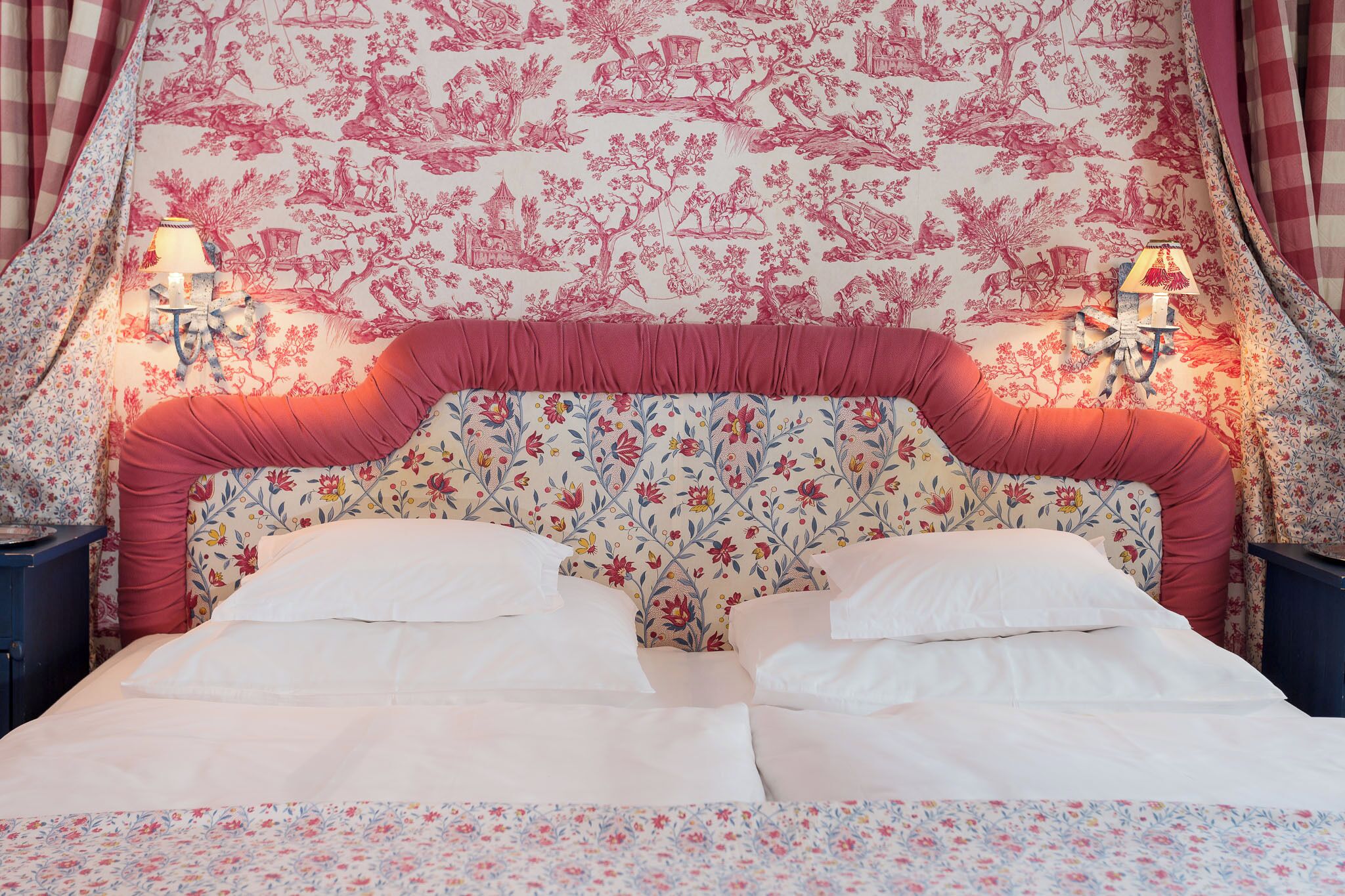 A bed with white linens, a floral-patterned headboard, and two bedside lamps.