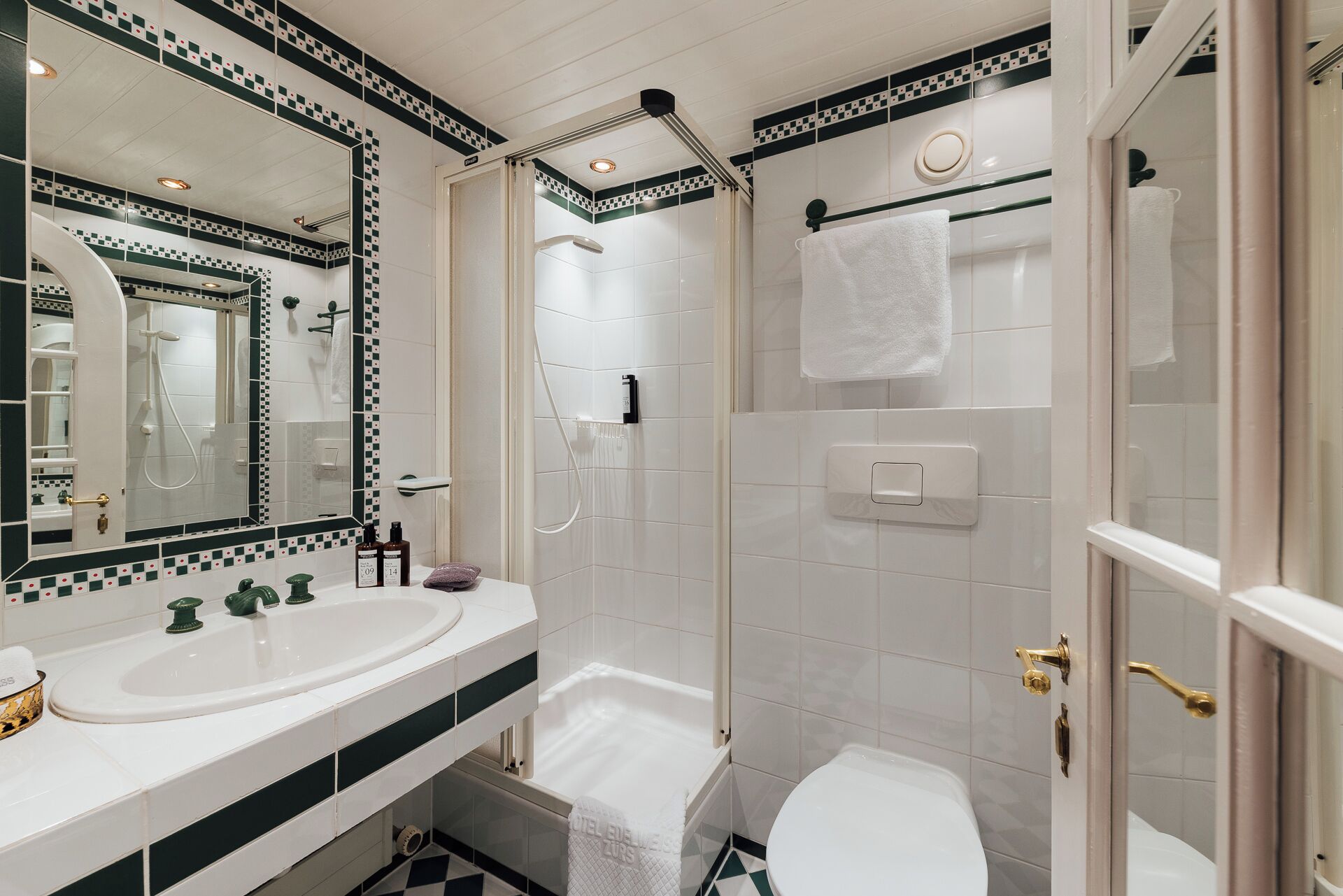 Een badkamer met een wit wastafel, een spiegel, een douche en een toilet.