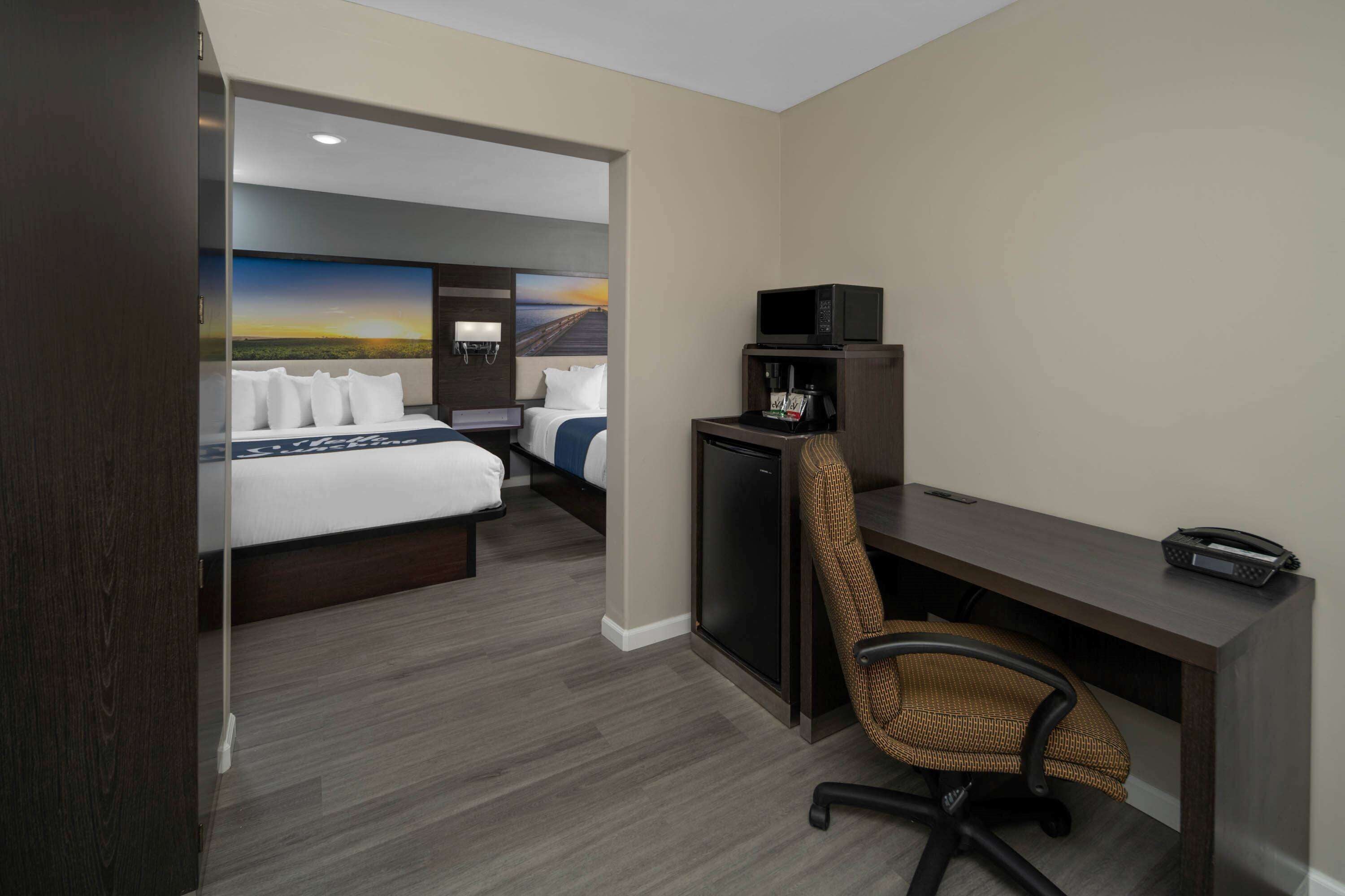 A hotel room with a bed, a desk, a chair, a television, and a microwave.