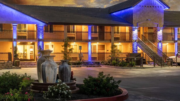 A hotel with multiple balconies, a central fountain, and a staircase leading to the upper floors. - Days Inn by Wyndham Galt/Elk Grove South (Galt)