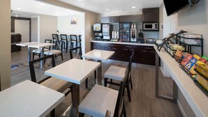 A modern kitchen with dark cabinets, a microwave, and a coffee station. There are multiple tables and chairs arranged for dining. - Days Inn by Wyndham Galt/Elk Grove South (Galt)