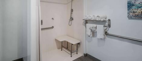 Uma casa de banho moderna com chuveiro, um banco e um porta-toalhas.