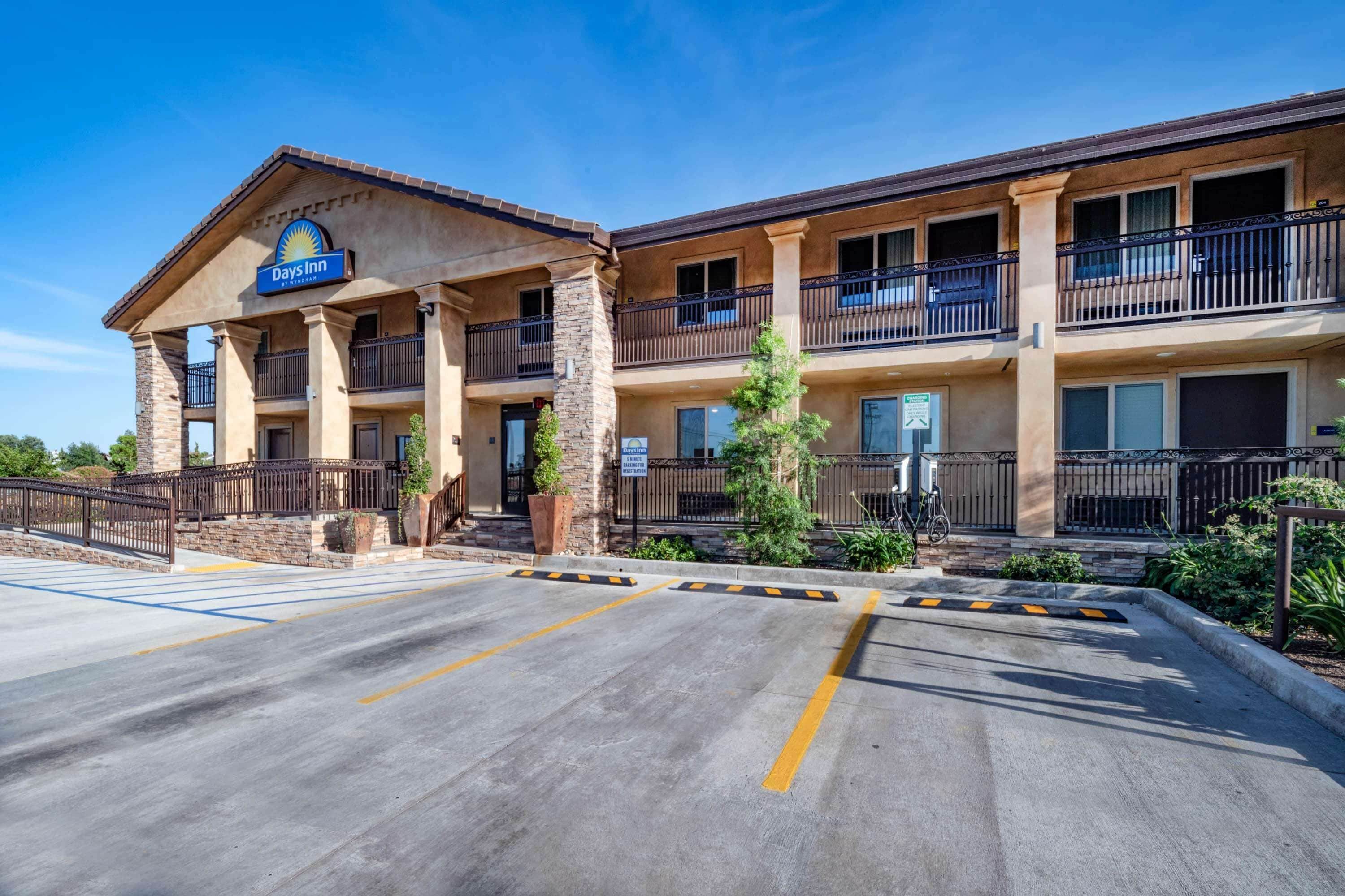 A Days Inn with a two-story building, a parking lot, and a landscaped area with plants.