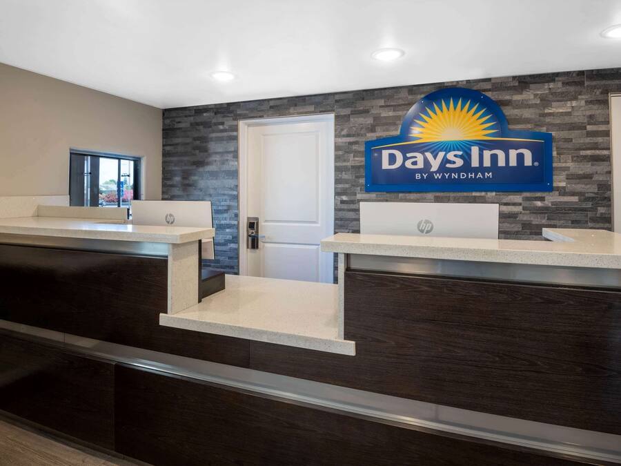 A reception area with a Days Inn sign, a reception desk, and a door leading to the interior.