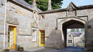A stone building with a cobblestone courtyard, two yellow doors, and an arched entrance. - Kennedy Cottage - Newly Refurbished 3 Bedroom Cottage on Blairquhan estate (Maybole)