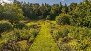 A garden with a central path leading to a gazebo, surrounded by various plants and trees. - Kennedy Cottage - Newly Refurbished 3 Bedroom Cottage on Blairquhan estate (Maybole)