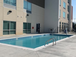 Una piscina junto a un edificio con ventanas y puerta grandes.
