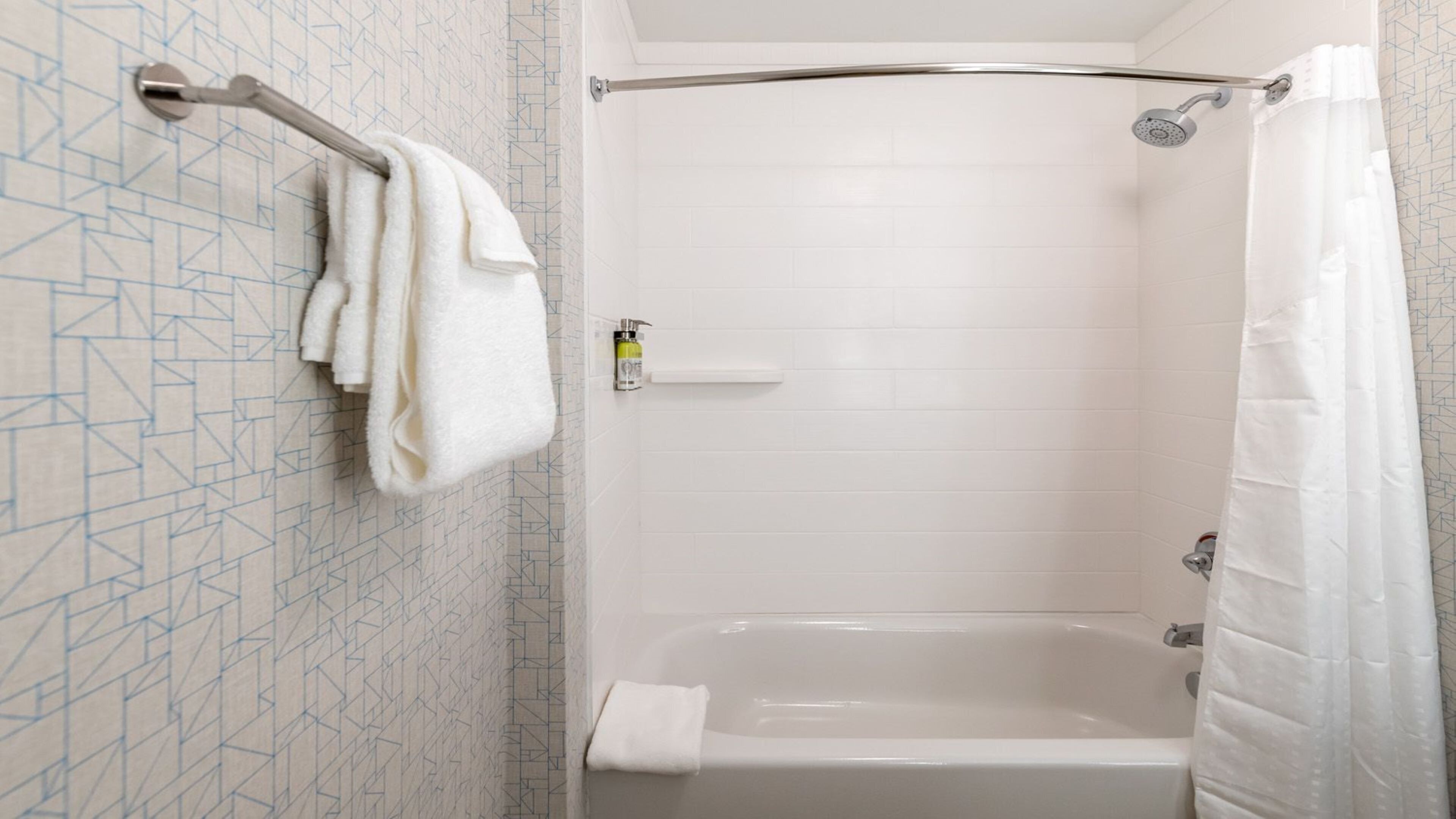 A shower with a glass door, a towel rack, and a shower curtain.