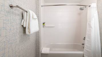 A shower with a glass door, a towel rack, and a shower curtain.