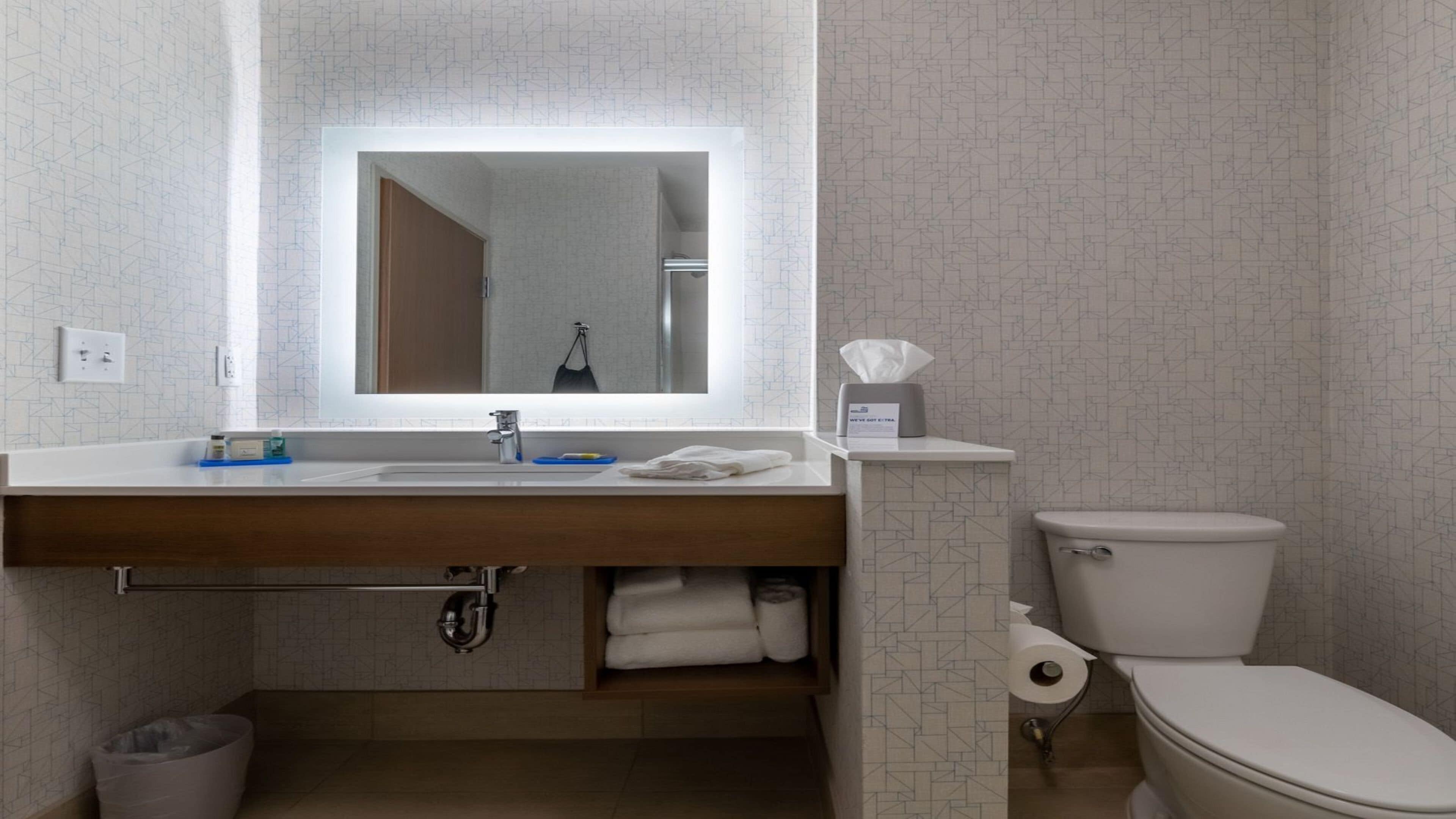Un baño moderno con un espejo grande, un lavabo blanco y un inodoro.
