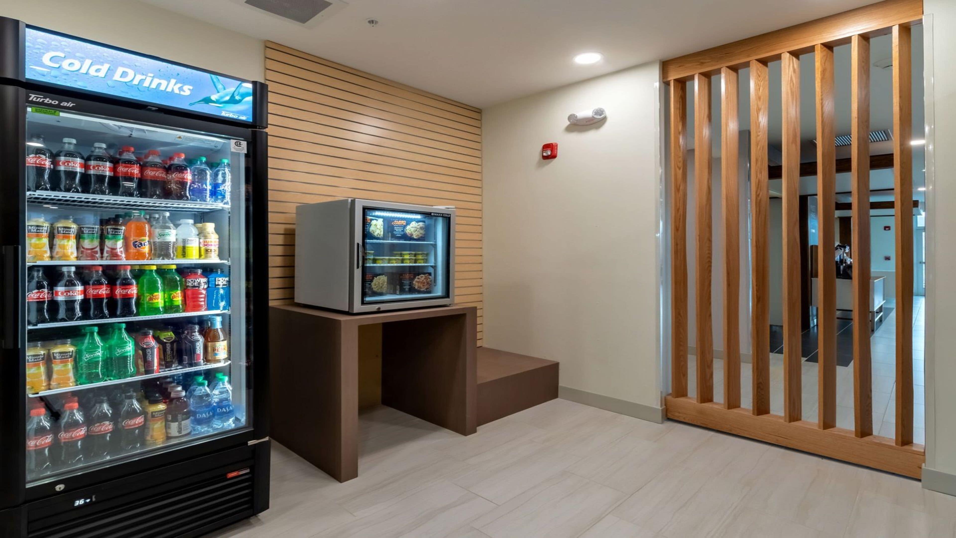 A vending machine with a variety of beverages and a small refrigerator with food items.