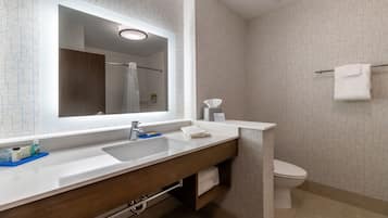 Ein modernes Badezimmer mit großem Spiegel, Waschbecken, Toilette und Handtuchhalter.