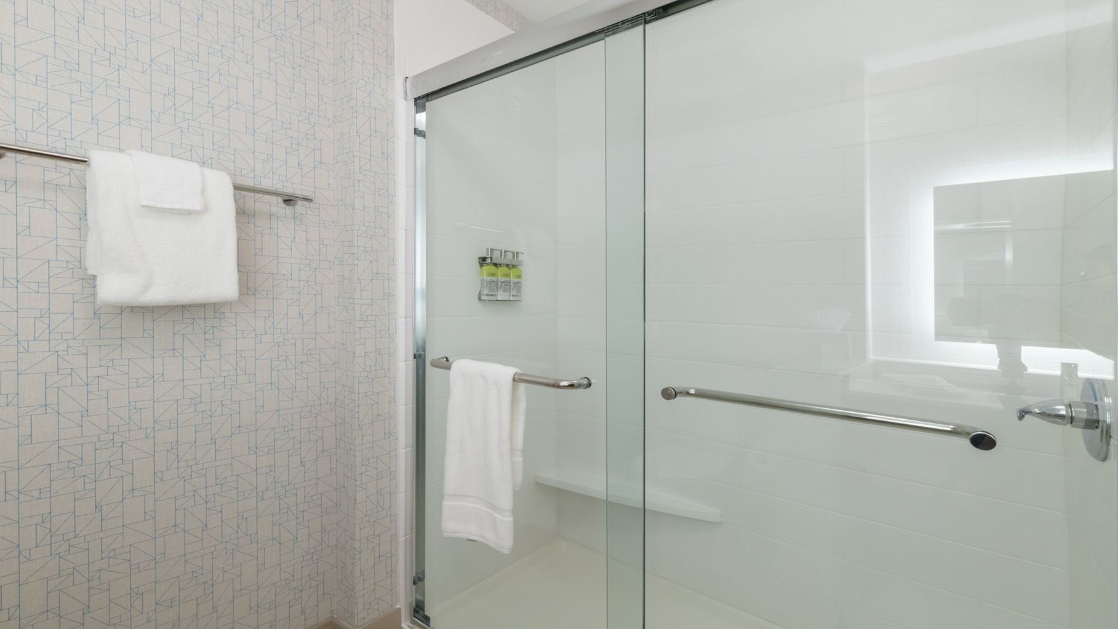 A modern bathroom with a glass shower door, a towel rack, and a glass-enclosed shower area.
