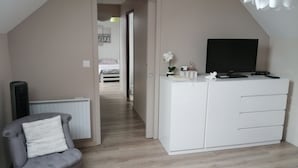 A bedroom with a bed, a desk with a TV, a chair, and a radiator. - Chambre et Appartement Zen de Beauval (Seigy)