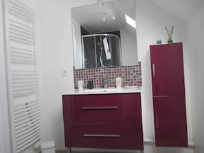 A bathroom with a white radiator, a mirror above a sink, and a red cabinet. - Chambre et Appartement Zen de Beauval (Seigy)