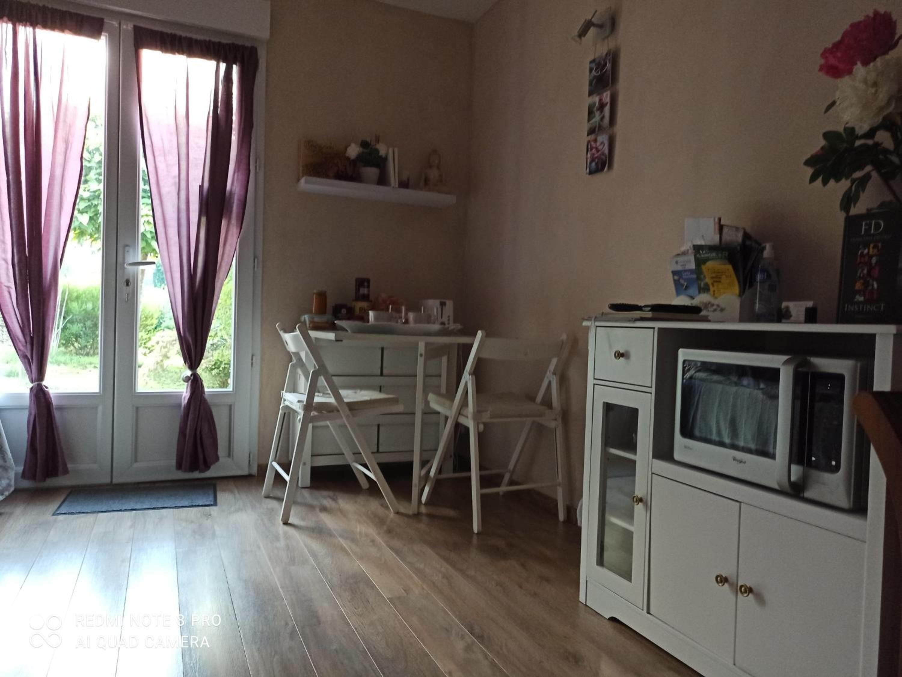 Eine kleine Küche mit einem weißen Schrank, einer Mikrowelle und einem Tisch mit Stühlen.