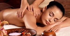 A person receiving a massage with a bowl of fruits and a candle on the table. - Chambre et Appartement Zen de Beauval (Seigy)