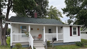 A single-story house with a porch, a mailbox, and a small garden area. - Updated home 2 blocks from water in Colonial Beach-come visit Driftwood Cottage! (Colonial Beach)