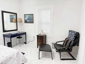 Un dormitorio con cama, escritorio, silla, cómoda y dos cuadros en la pared.