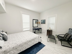 Un dormitorio con cama, escritorio, silla y cómoda.