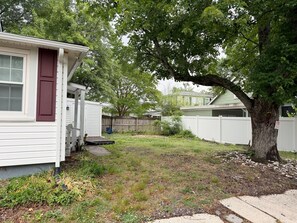 A residential area with a white house, a tree, and a white fence.