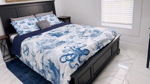 A bedroom with a bed, a nightstand, a window with blinds, and a painting on the wall. - Updated home 2 blocks from water in Colonial Beach-come visit Driftwood Cottage! (Colonial Beach)