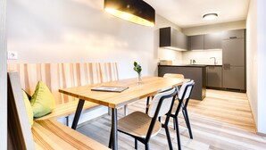A modern kitchen with a wooden dining table, black chairs, and a pendant light.