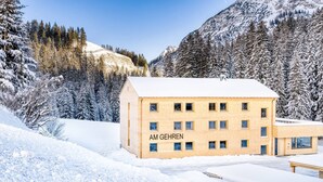 A building labeled "AM GEHREN" with a snow-covered landscape and mountains in the background.
