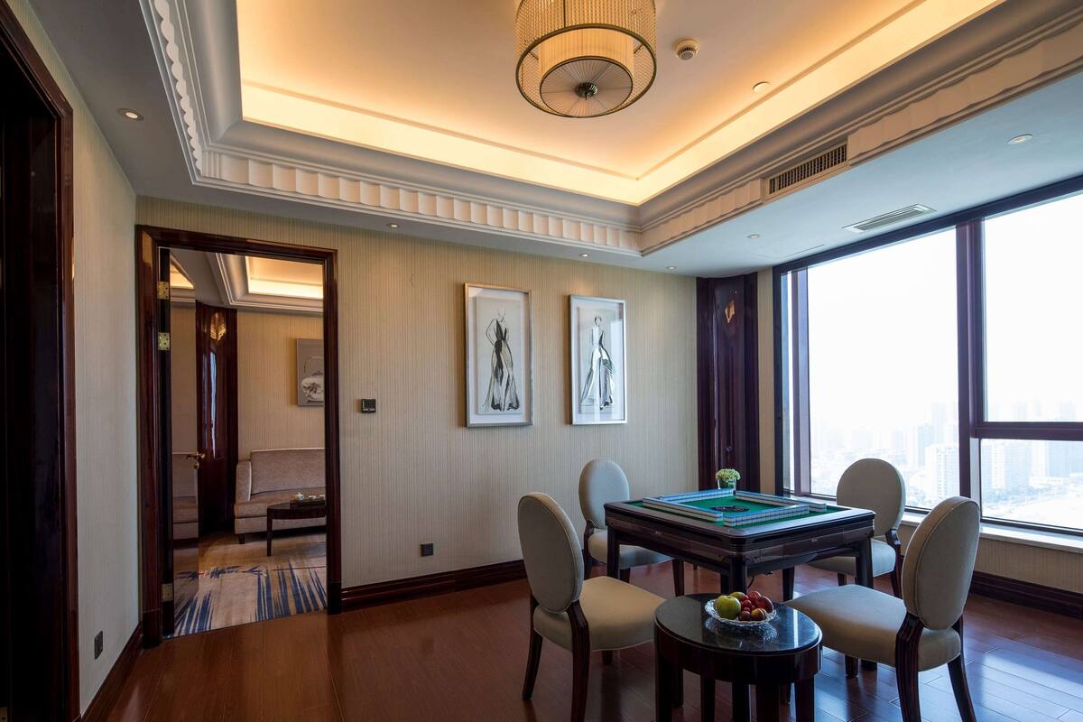 A spacious room with a wooden floor, a billiards table, and a view of the city through large windows.