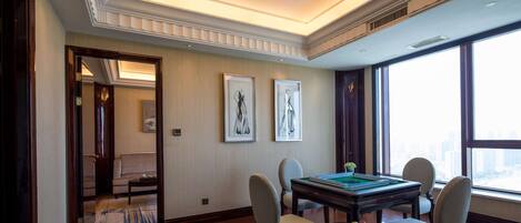 A spacious room with a wooden floor, a billiards table, and a view of the city through large windows.