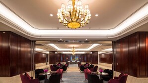 A hotel lobby with a grand chandelier, dark wood paneling, and a long table with chairs. - Wyndham Zhuji West (Shaoxing)