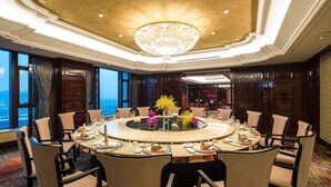 A round dining table with chairs, a chandelier, and a view of the city. - Wyndham Zhuji West (Shaoxing)