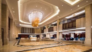 A spacious lobby with a large marble floor, a grand chandelier, and a reception desk. - Wyndham Zhuji West (Shaoxing)